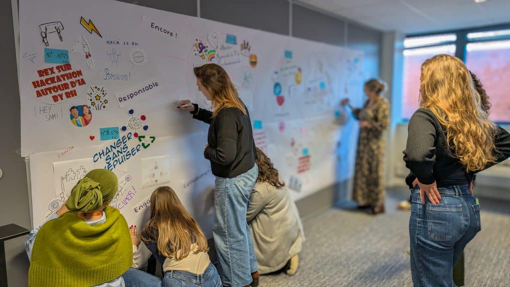 Des collaborateurs écrivent des mentions sur la fresque murale de feedback.